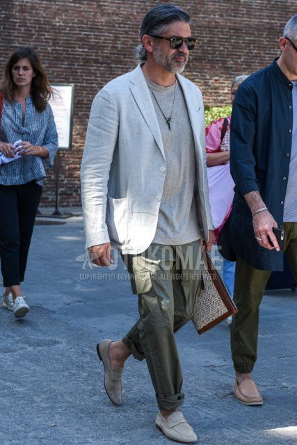 Men's coordinate and outfit with black eyewear sunglasses, plain white tailored jacket, plain gray t-shirt, plain olive green cargo pants, suede gray coin loafer leather shoes, brown/beige bag clutch/second bag/drawstring.