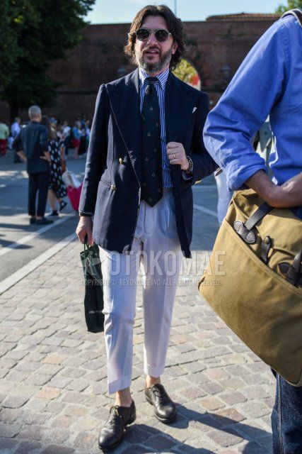 Men's coordinate and outfit with plain gray sunglasses, plain navy tailored jacket, white/blue striped shirt, plain white beltless pants, brown straight tip leather shoes, and olive green regimental tie.