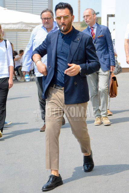 Men's coordinate and outfit with round plain silver sunglasses, plain navy tailored jacket by Lardini, plain navy polo shirt, plain black leather belt, plain beige chinos, plain beige ankle pants, and black wingtip leather shoes.