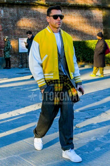 Men's winter/autumn coordinate and outfit with plain black sunglasses, plain yellow stadium jacket, plain white t-shirt, white/black checked tailored jacket, wool gray striped slacks, and Nike Air Force 1 white low-cut sneakers.