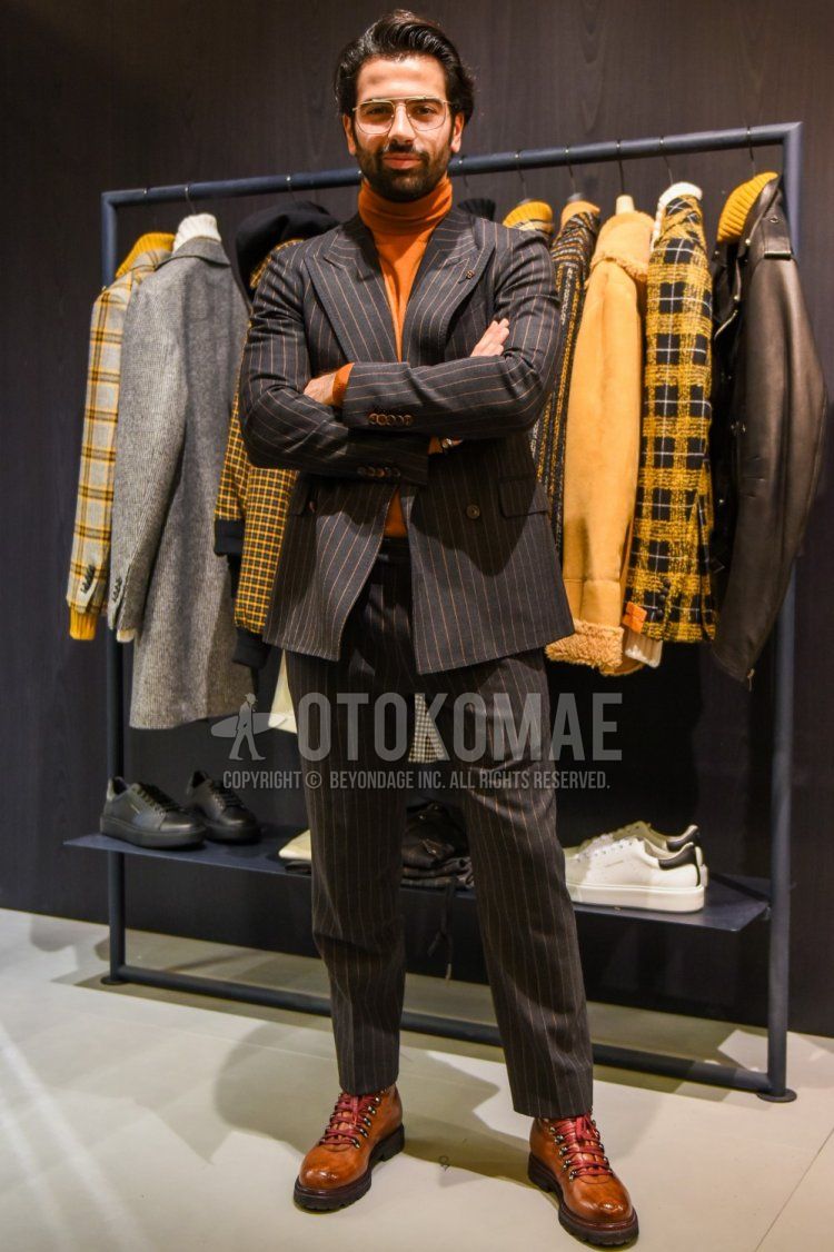 Men's fall/spring coordination and outfit with plain gold glasses, plain orange turtleneck knit, brown boots, and gray striped suit.