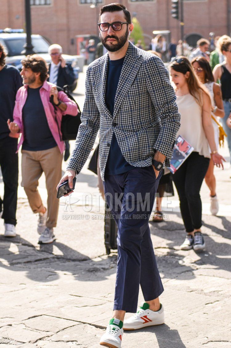Men's coordinate and outfit with plain black sunglasses, gray checked tailored jacket, plain blue t-shirt, plain navy cotton pants, plain navy ankle pants, and white low-cut sneakers.