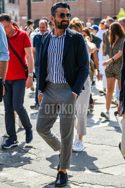 Men's coordinate and outfit with plain black sunglasses, plain navy tailored jacket, navy/white striped shirt, plain gray beltless pants with Gurkha pants, navy suede shoes leather shoes, navy loafers leather shoes.