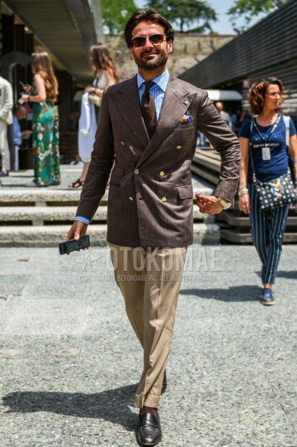 Men's coordinate and outfit with plain gold sunglasses, plain brown tailored jacket, light blue striped shirt, plain brown cotton pants, plain brown socks, brown coin loafer leather shoes, and plain brown tie.