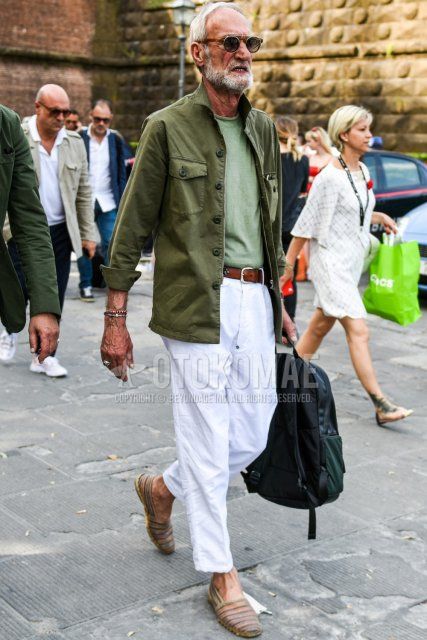 Men's coordinate and outfit with plain brown sunglasses, plain olive green shirt jacket, plain green t-shirt, plain brown leather belt, plain white cotton pants, and multi-colored espadrilles.