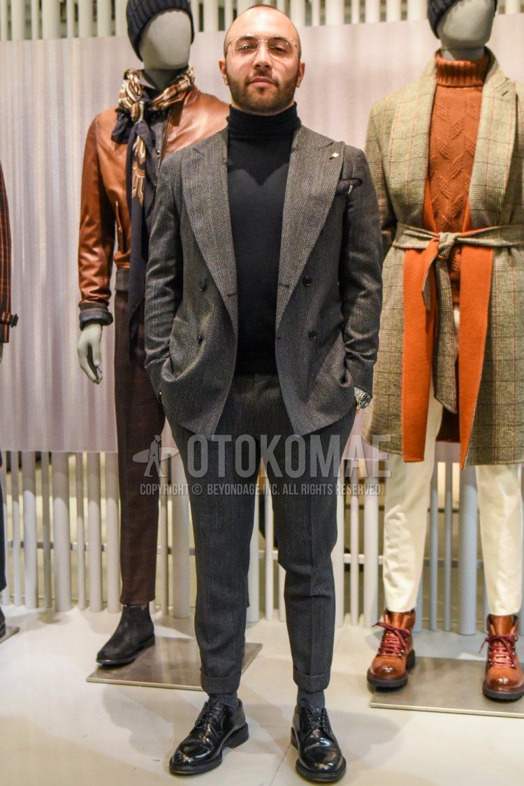 Spring and fall men's coordinate and outfit with teardrop solid silver glasses, dark gray solid turtleneck knit, solid gray socks, black plain toe leather shoes, and solid gray suit.