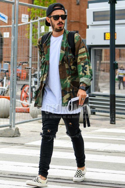 Men's coordinate and outfit with plain black baseball cap, plain sunglasses, multi-colored camouflage M-65, plain white t-shirt, plain black damaged jeans, and white slip-on sneakers by Vans.