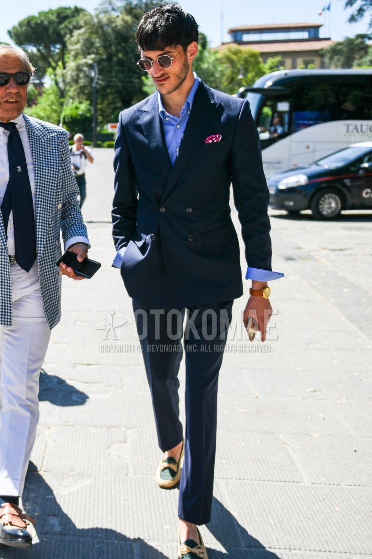 Men's coordination and outfit with plain brown/gold sunglasses, plain light blue shirt, beige/olive green leather shoes, and plain navy suit.