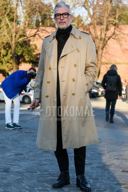Men's fall/winter outfit with Tom Ford plain black glasses, plain beige trench coat, plain black trucker jacket, plain black turtleneck knit, plain black slacks, and black boots.