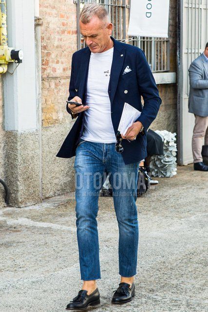 Men's spring/fall/summer coordination and outfit with plain navy tailored jacket, white lettered t-shirt, plain blue denim/jeans, and black tassel loafer leather shoes.