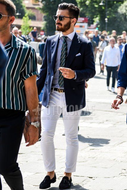 Men's spring/summer/fall outfit with plain silver/black sunglasses, plain navy tailored jacket, black/white striped shirt, Gucci black decal logo leather belt, plain white cotton pants, and black tassel loafer leather shoes.