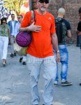Men's summer coordinate and outfit with plain navy baseball cap, plain black sunglasses, Adidas orange one-point T-shirt, plain white cargo pants, and Asics black low-cut sneakers.