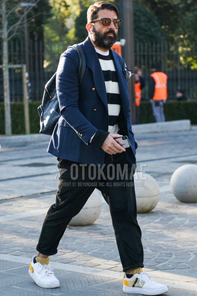 Men's spring and fall outfit and outfit with brown tortoiseshell sunglasses, plain navy tailored jacket, white and black striped sweater, dark gray plain easy pants, white low-cut sneakers, and gray bag backpack.