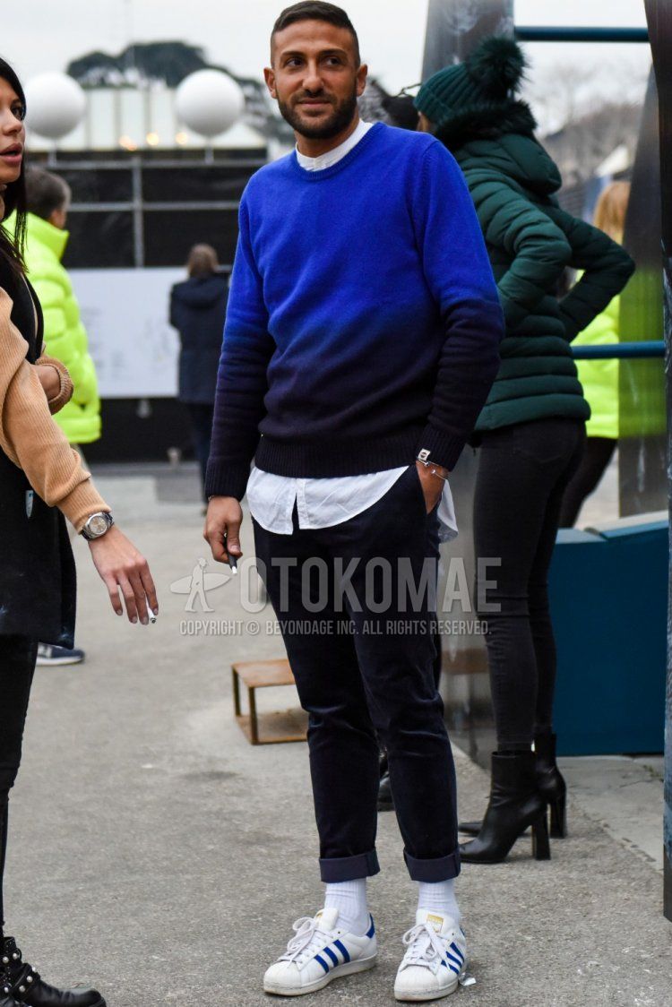 Men's fall coordinate and outfit with plain blue sweater, plain white shirt, plain black denim/jeans, plain white socks, and white low-cut Adidas sneakers.