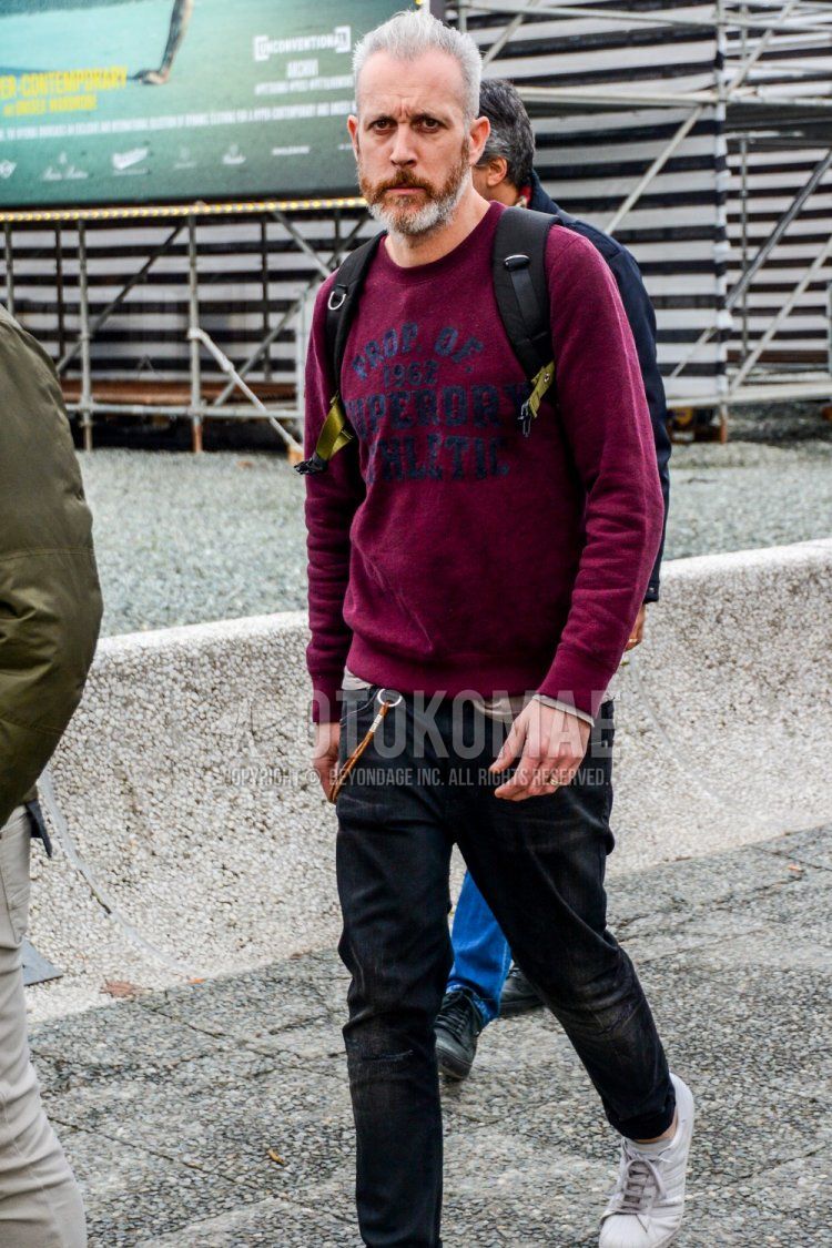 Spring and fall men's coordinate and outfit with red lettered sweatshirt, plain black denim/jeans, and white low-cut sneakers.