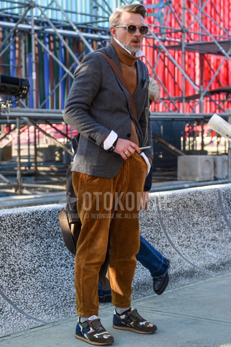 Spring and fall men's coordinate with clear solid sunglasses, solid gray tailored jacket, solid brown turtleneck knit, solid white shirt, solid brown winter pants (corduroy, velour), solid gray socks, olive green/navy low-cut sneakers. Dressing.