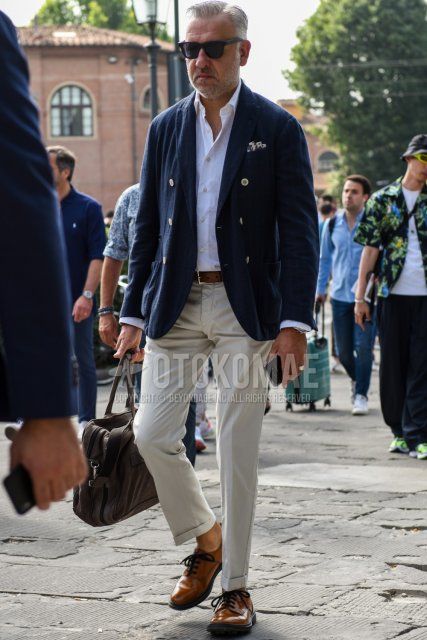 Men's spring and fall outfit and outfit with plain black Wellington sunglasses, plain navy tailored jacket, plain white shirt, plain brown leather belt, plain white slacks, plain brown plain toe leather shoes, and plain brown Boston bag.