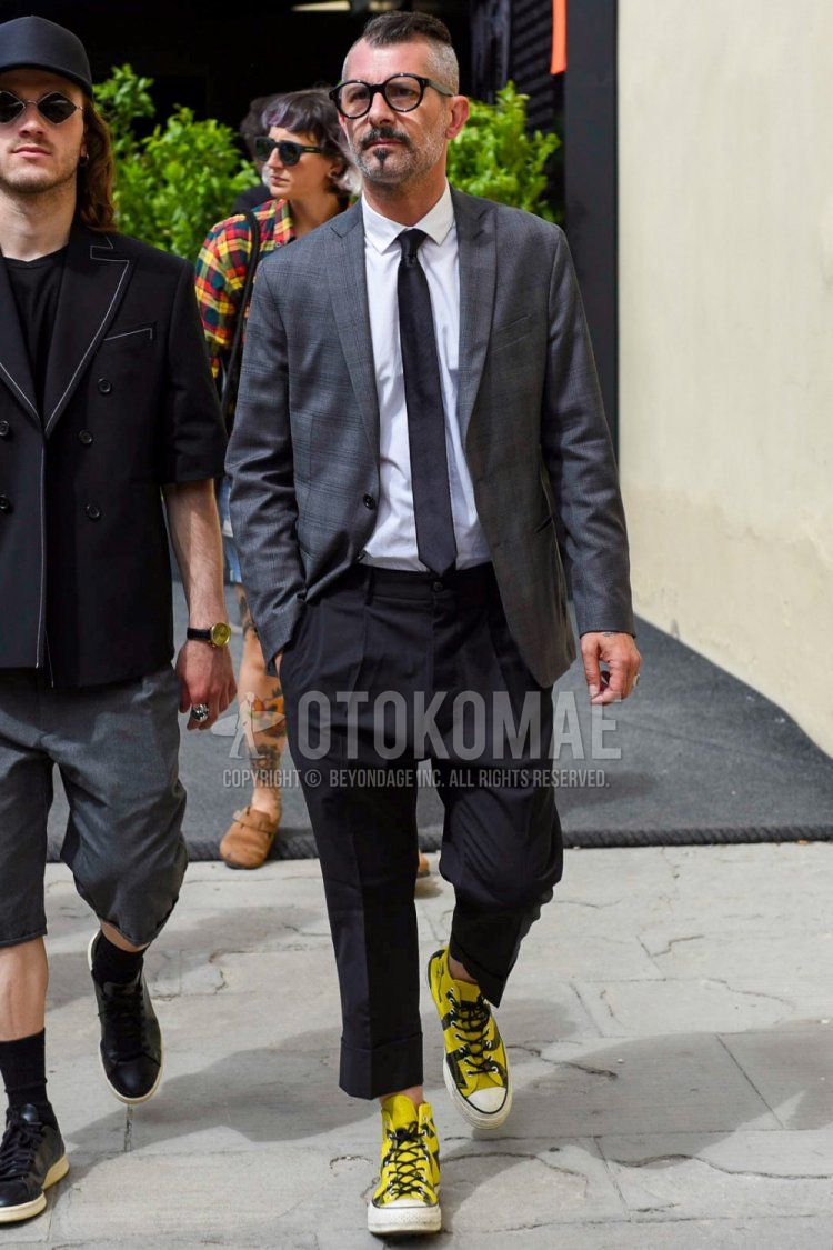 Men's spring and autumn coordinate and outfit with plain black glasses, plain gray tailored jacket, plain white shirt, dark gray plain slacks, yellow high-cut sneakers, and plain black tie.