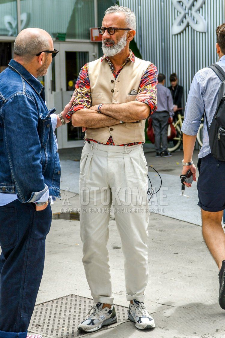 Men's spring/summer/autumn coordinate and outfit with plain glasses, plain gilet, multi-colored top/inner shirt, plain white pleated pants, plain white beltless pants, and white low-cut sneakers by New Balance.