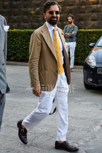 Men's spring and fall outfit with gold and black plain sunglasses, beige plain tailored jacket, white plain shirt, white plain slacks, brown monk shoes leather shoes, and yellow tie tie.