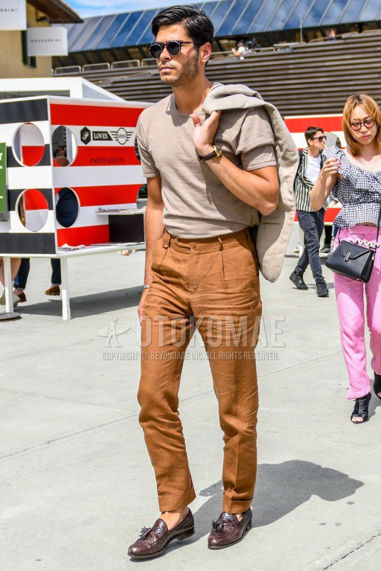 Men's spring, summer, and fall outfit with solid color sunglasses, solid color brown sweater, solid color orange slacks, and brown tassel loafer leather shoes.