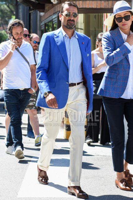 Spring and fall men's coordinate and outfit with clear solid sunglasses, light blue solid tailored jacket, light blue and white striped shirt, brown solid leather belt, white solid slacks, red solid socks, brown tassel loafer leather shoes.