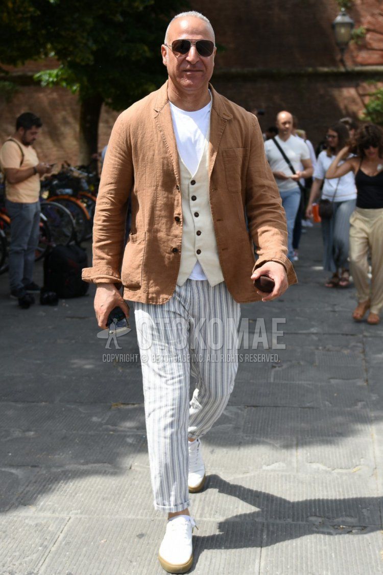 Men's spring, summer, and fall outfits with plain black sunglasses, plain brown tailored jacket, plain white t-shirt, plain beige gilet, gray striped slacks, gray striped ankle pants, and white low-cut sneakers.