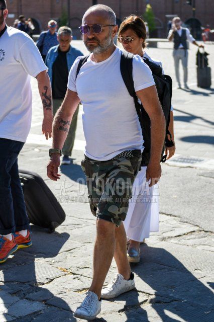 Men's summer coordinate and outfit with plain silver sunglasses, plain white t-shirt, plain gray/white mesh belt, green camouflage cargo pants, green camouflage shorts, and white low-cut sneakers.
