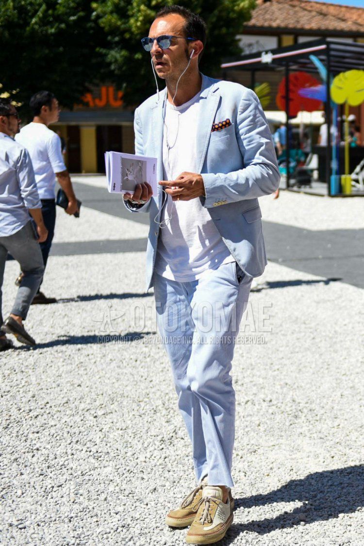 Men's spring/summer coordinate and outfit with Ray-Ban plain blue sunglasses, plain white T-shirt, beige low-cut sneakers, and plain light blue suit.