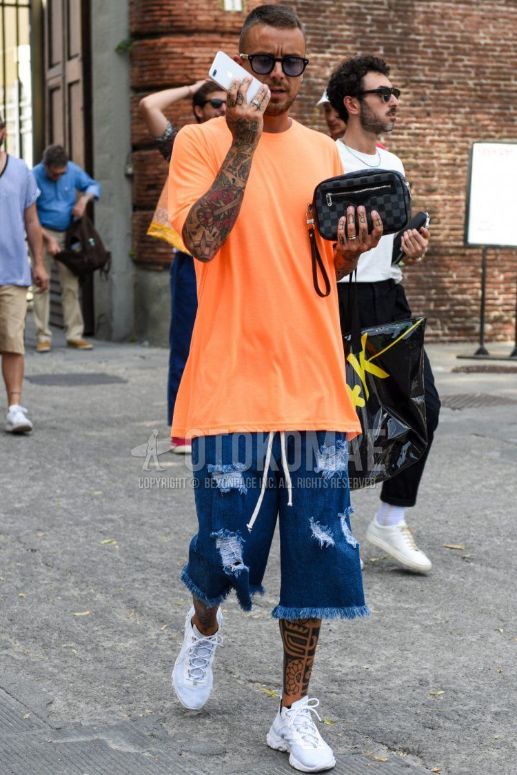 Men's summer coordinate and outfit with plain black sunglasses, plain orange t-shirt, plain blue shorts, white low-cut sneakers, and Louis Vuitton gray checked clutch bag/second bag/drawstring.