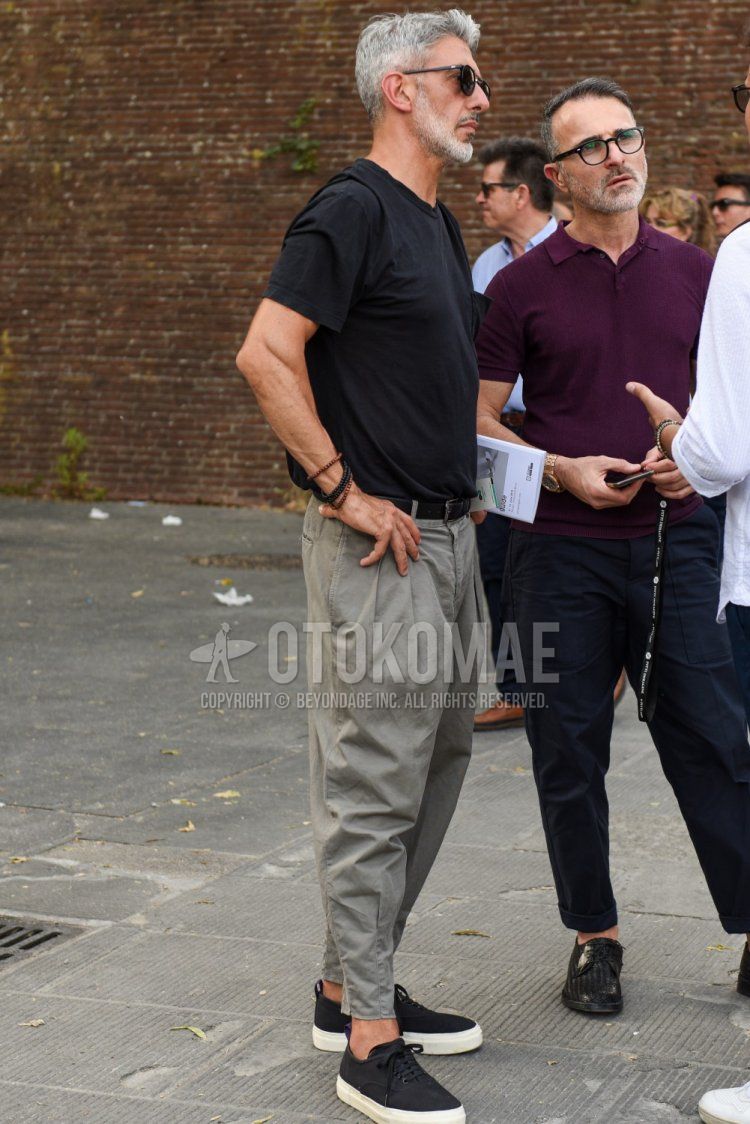 Men's summer coordinate and outfit with plain black sunglasses, plain black t-shirt, plain black leather belt, plain gray ankle pants, and black low-cut sneakers.