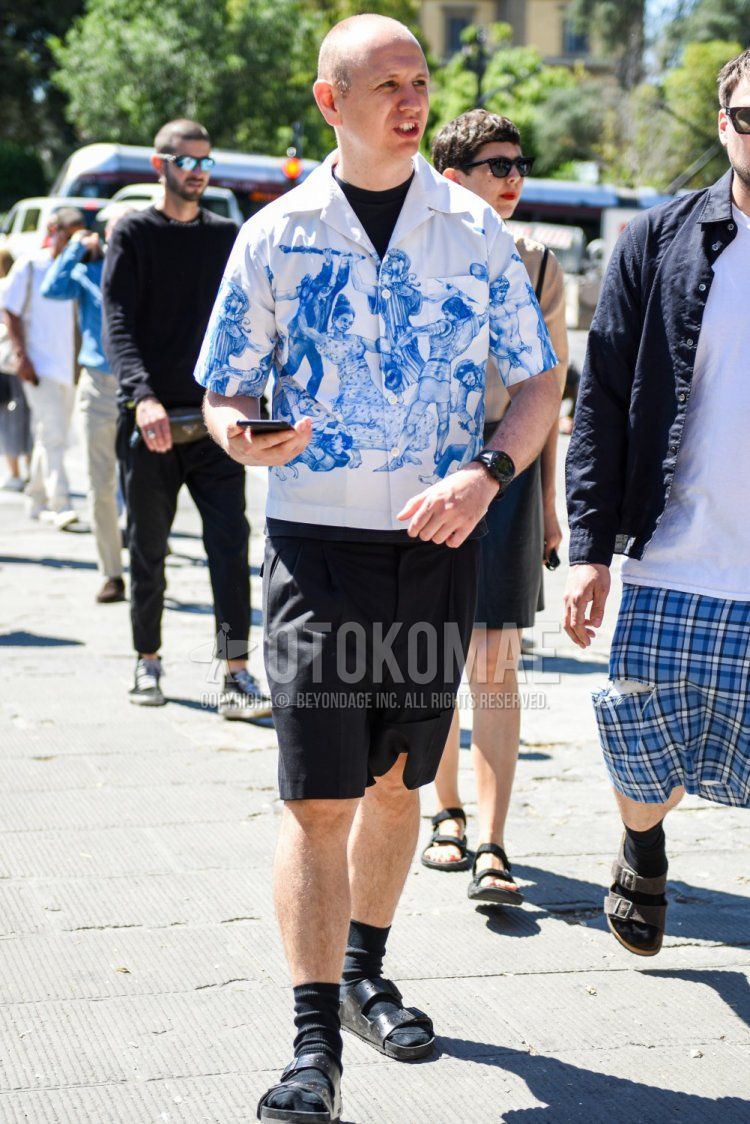 Summer men's coordinate and outfit with short sleeves open collar white top/inner shirt, plain black t-shirt, plain black shorts, plain black socks, and black leather sandals.
