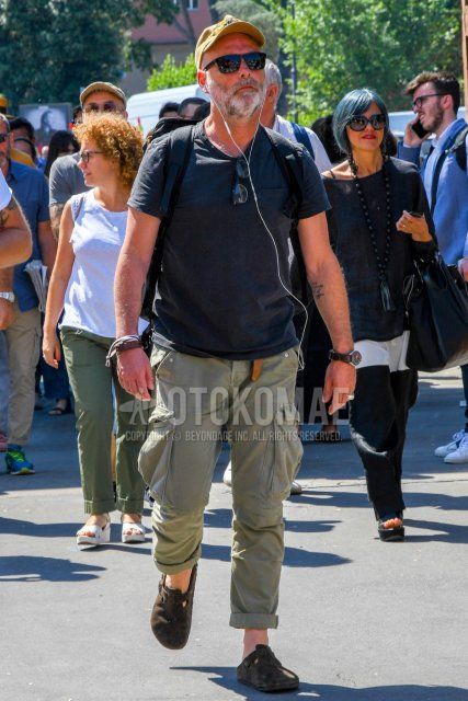 Summer men's coordinate and outfit with plain yellow baseball cap, plain sunglasses, plain black t-shirt, plain olive green cargo pants, and brown leather sandals.