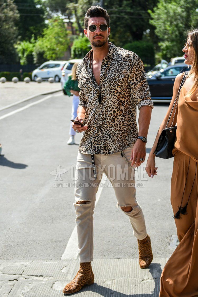 Men's spring, summer, and fall coordination and outfit with plain gold sunglasses, yellow leopard shirt, plain beige damaged jeans, and brown boots.