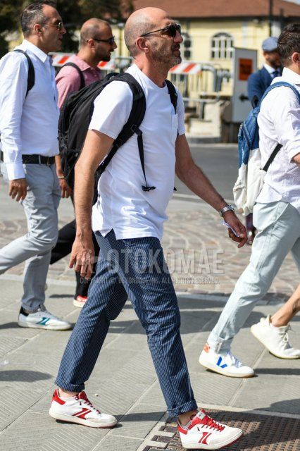 Men's summer coordinate and outfit with plain black sunglasses, plain white t-shirt, navy striped slacks, white low-cut sneakers, and plain black backpack.