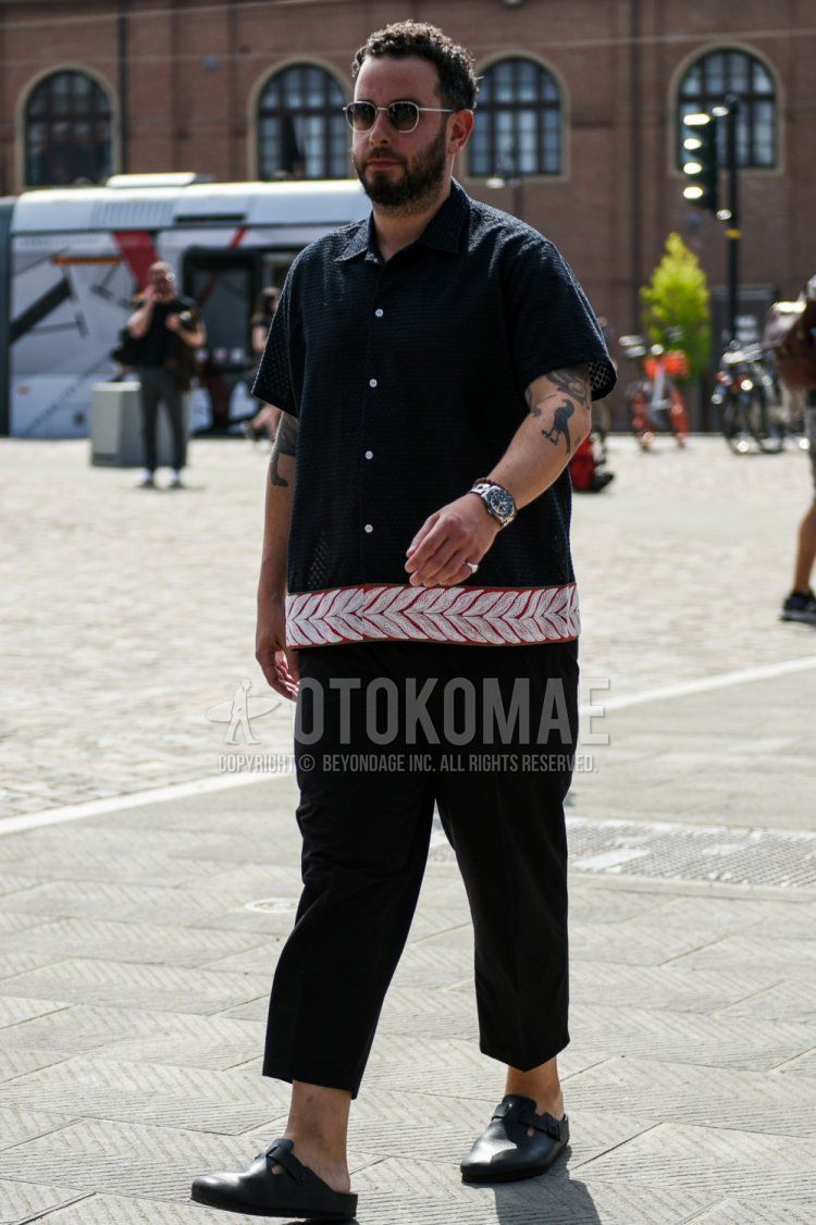 Men's summer coordinate and outfit with plain silver sunglasses, short-sleeved black top/inner shirt, plain black and gray cropped pants, and black leather sandals.