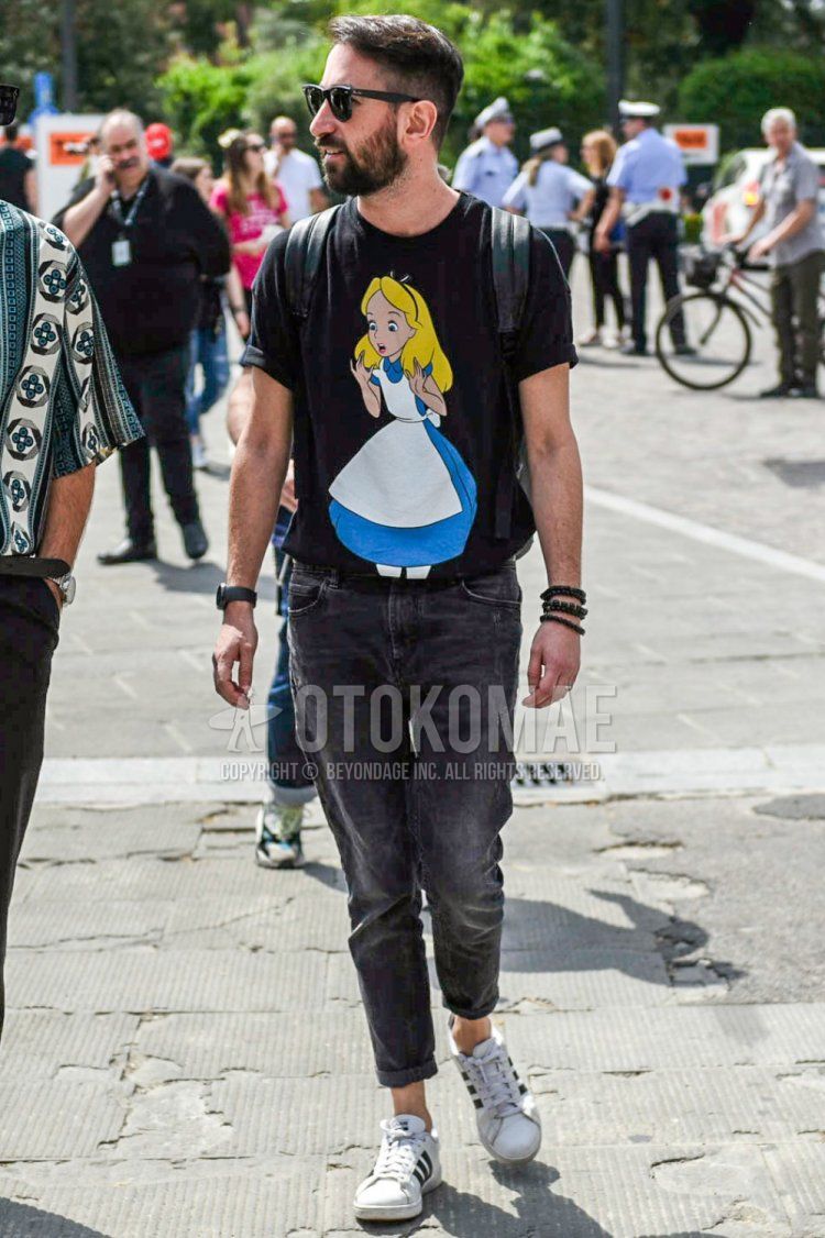 ウェリントン レイバン ウェイファーラーの黒無地のサングラス、黒グラフィックのTシャツ、グレー無地のデニム/ジーンズ、アディダスの白ローカットのスニーカーを合わせた夏のメンズコーデ・着こなし。