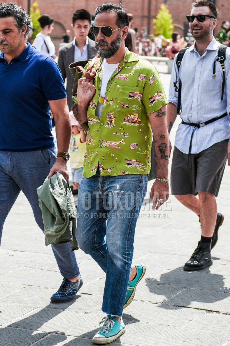 Summer men's coordinate and outfit with teardrop gold/black plain sunglasses, green top/inner shirt, plain white t-shirt, plain blue damaged jeans, and light blue low-cut sneakers.