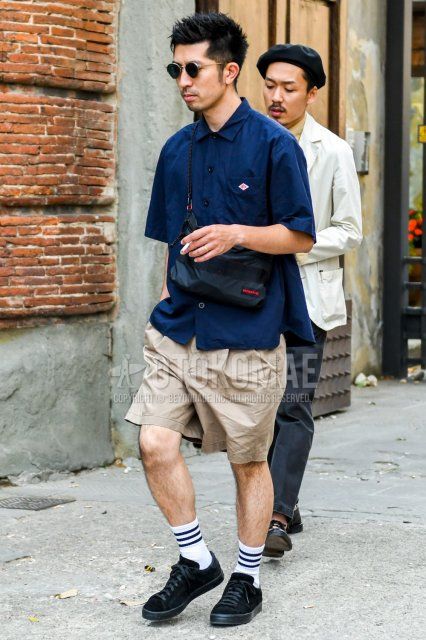 Men's summer coordinate and outfit with plain black sunglasses, plain navy shirt, plain beige shorts, white striped socks, black low-cut sneakers, and a black one-pointed sacoche from Bliffing.