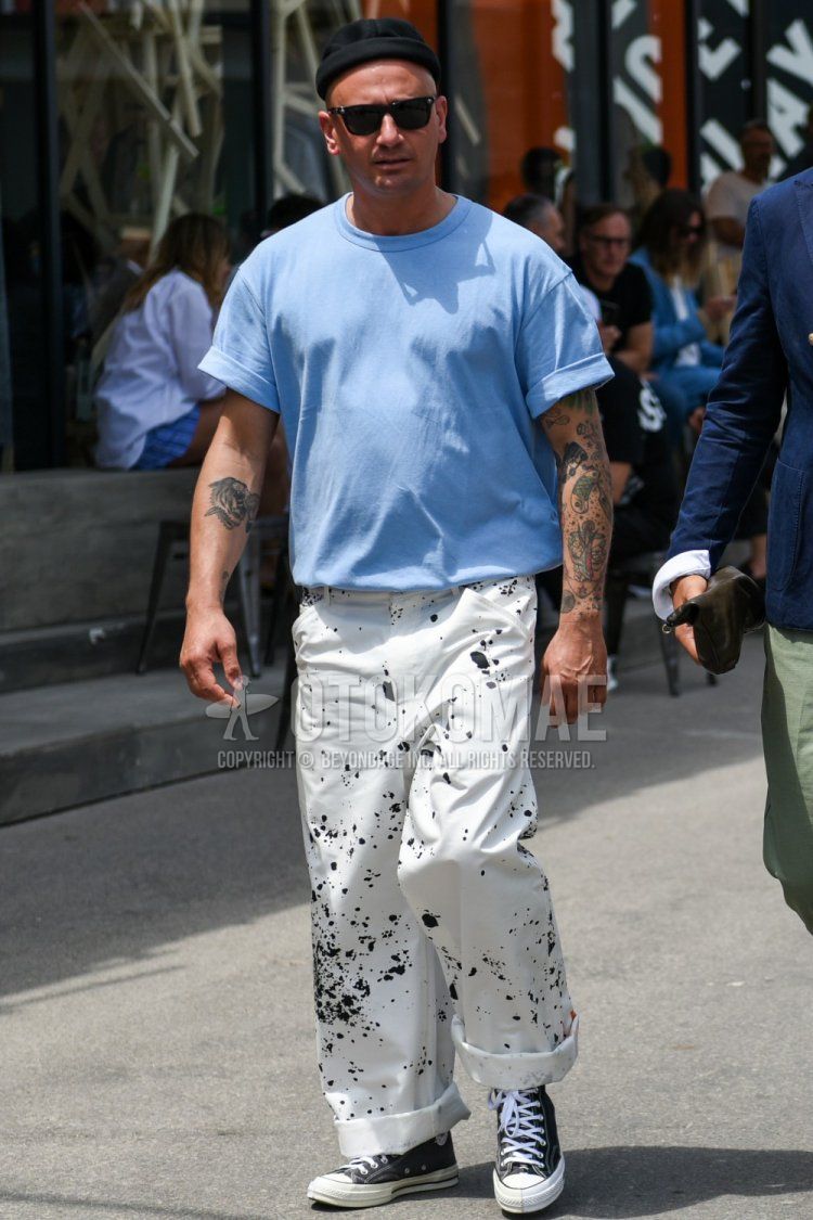Summer men's coordinate and outfit with plain black knit cap, plain black sunglasses, plain light blue t-shirt, white graphic chinos, and black high-cut Converse All Star sneakers.
