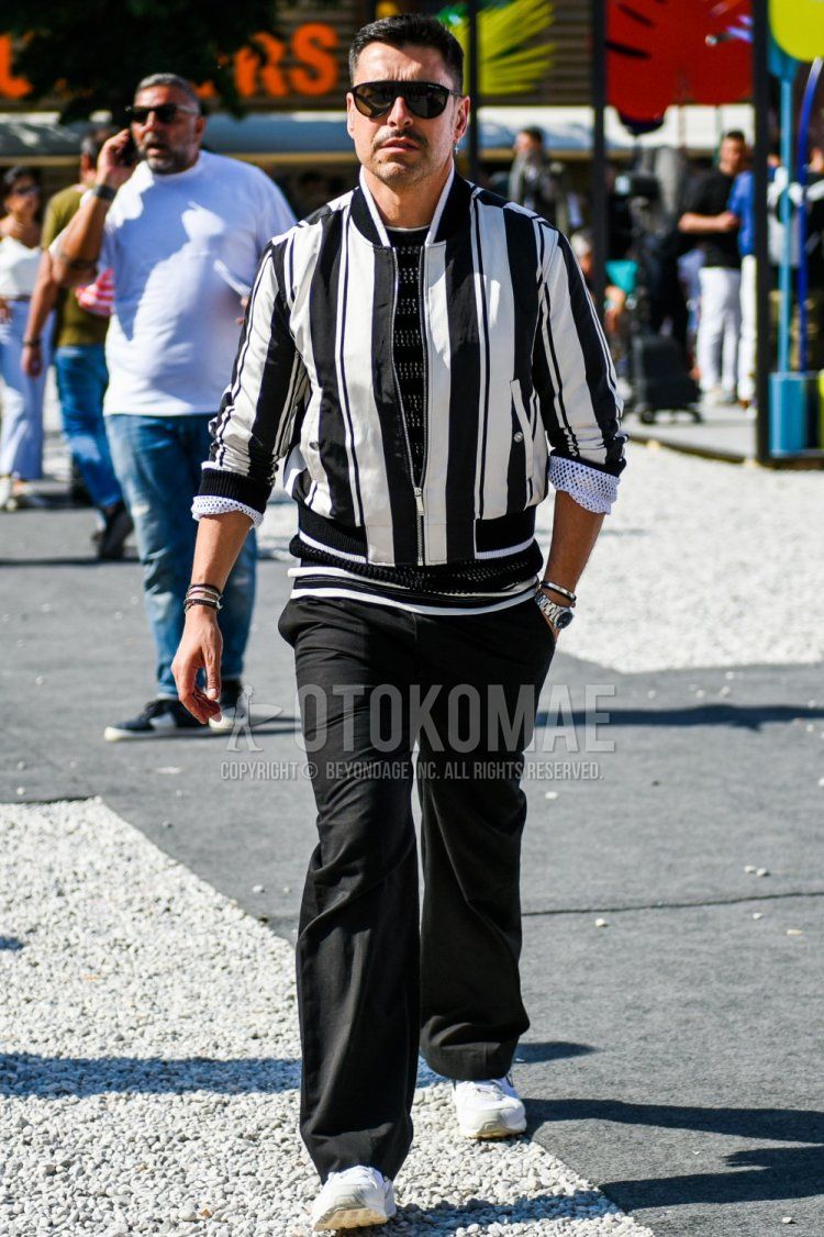 Men's spring, summer, and fall coordinate and outfit with plain black sunglasses, white and black striped MA-1, plain black T-shirt, plain black wide pants, and white low-cut sneakers.