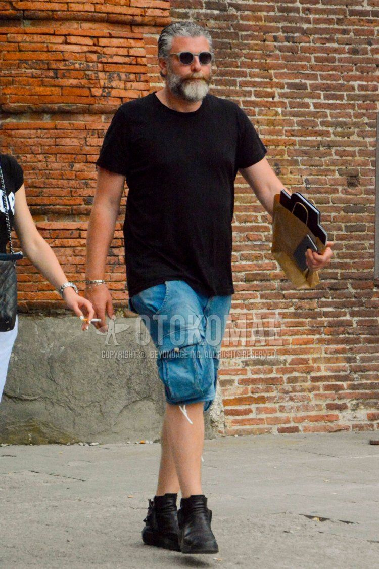 A summer men's coordinate and outfit with plain gray sunglasses, plain black t-shirt, solid blue shorts, solid blue denim/jeans, and black high-cut sneakers.