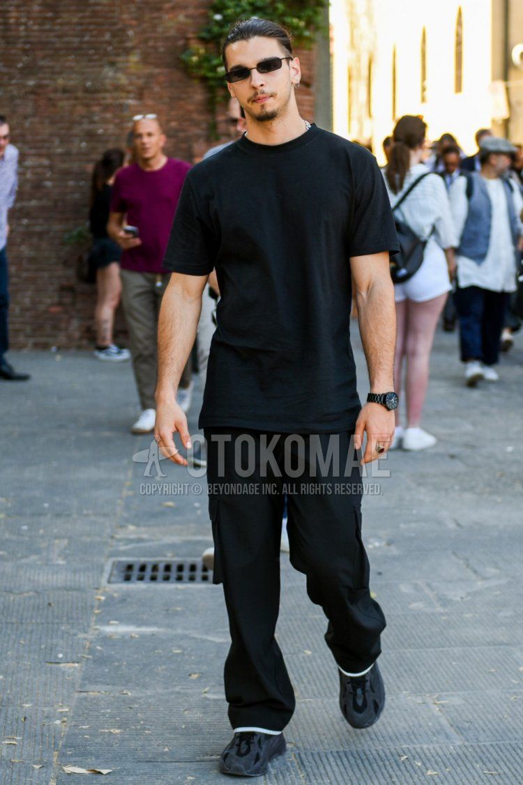 Men's summer coordinate and outfit with plain black sunglasses, plain black t-shirt, plain black wide-leg pants, and black low-cut Adidas sneakers.