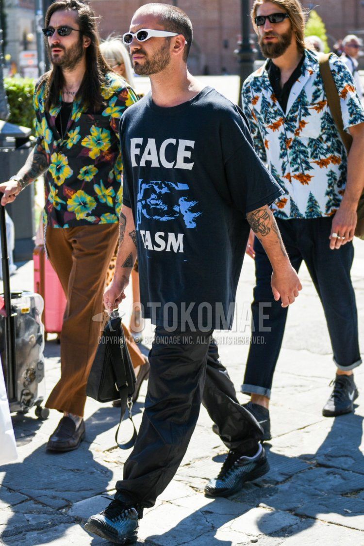 Men's summer coordinate and outfit with plain white sunglasses, black graphic t-shirt, plain black jogger pants/ribbed pants, and gray low-cut sneakers.