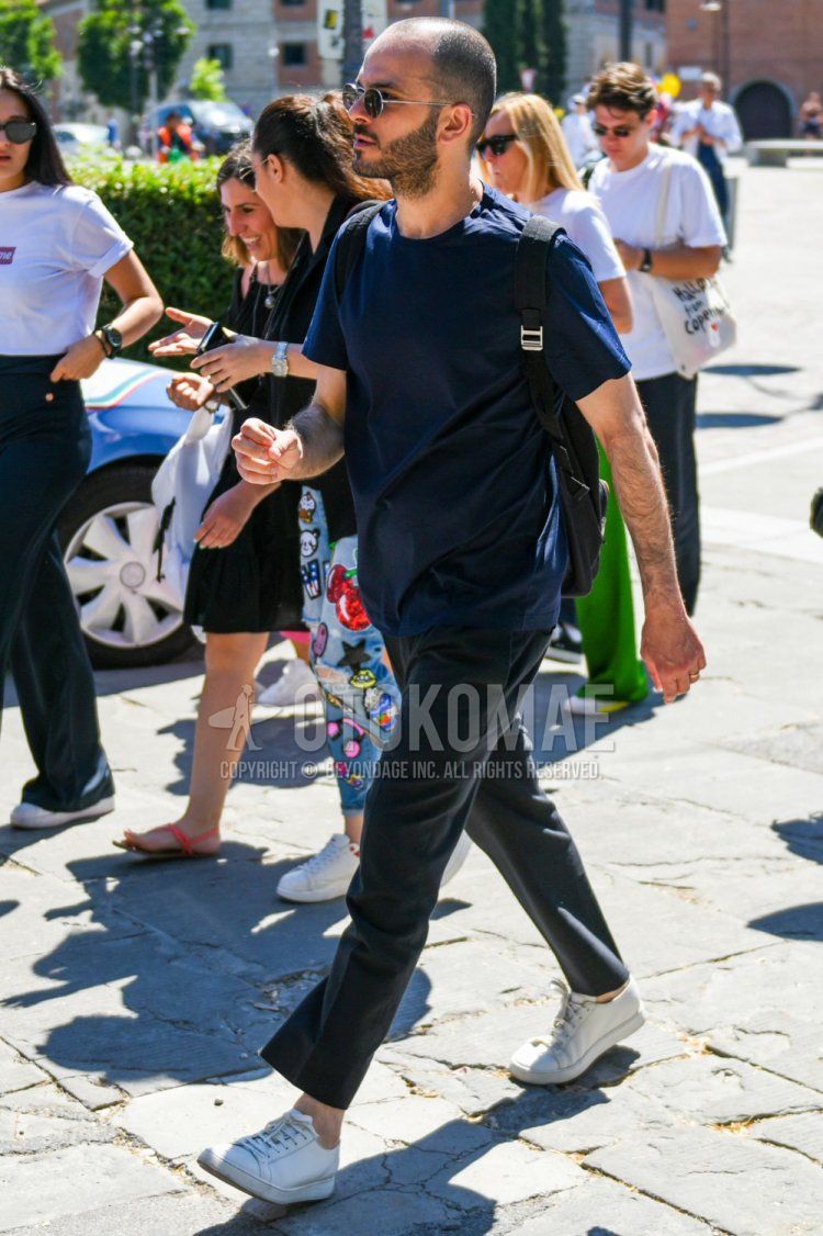 Men's summer coordinate and outfit with plain silver/black sunglasses, plain navy t-shirt, dark gray plain ankle pants, and white low-cut sneakers.