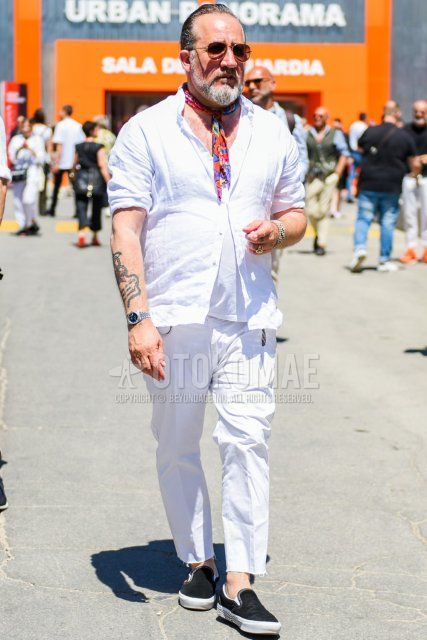 Spring/summer men's coordinate/outfit with teardrop gold/brown solid sunglasses, multi-colored stole bandana/neckerchief, linen solid white shirt, linen solid white t-shirt, solid white ankle pants, solid cotton pants, and black slip-on sneakers.