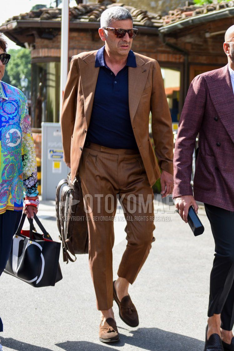Men's spring and summer coordinate and outfit with brown tortoiseshell sunglasses, plain navy polo shirt, suede brown tassel loafer leather shoes, plain brown backpack, and plain brown suit.