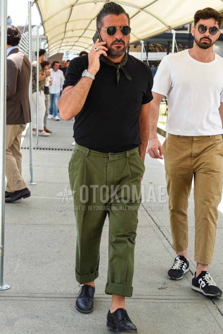 黒・ゴールド無地のサングラス、オリーブグリーン・黒ストールのバンダナ/ネッカチーフ、黒無地のTシャツ、オリーブグリーン無地のチノパン、黒プレーントゥの革靴を合わせた夏のメンズコーデ・着こなし。