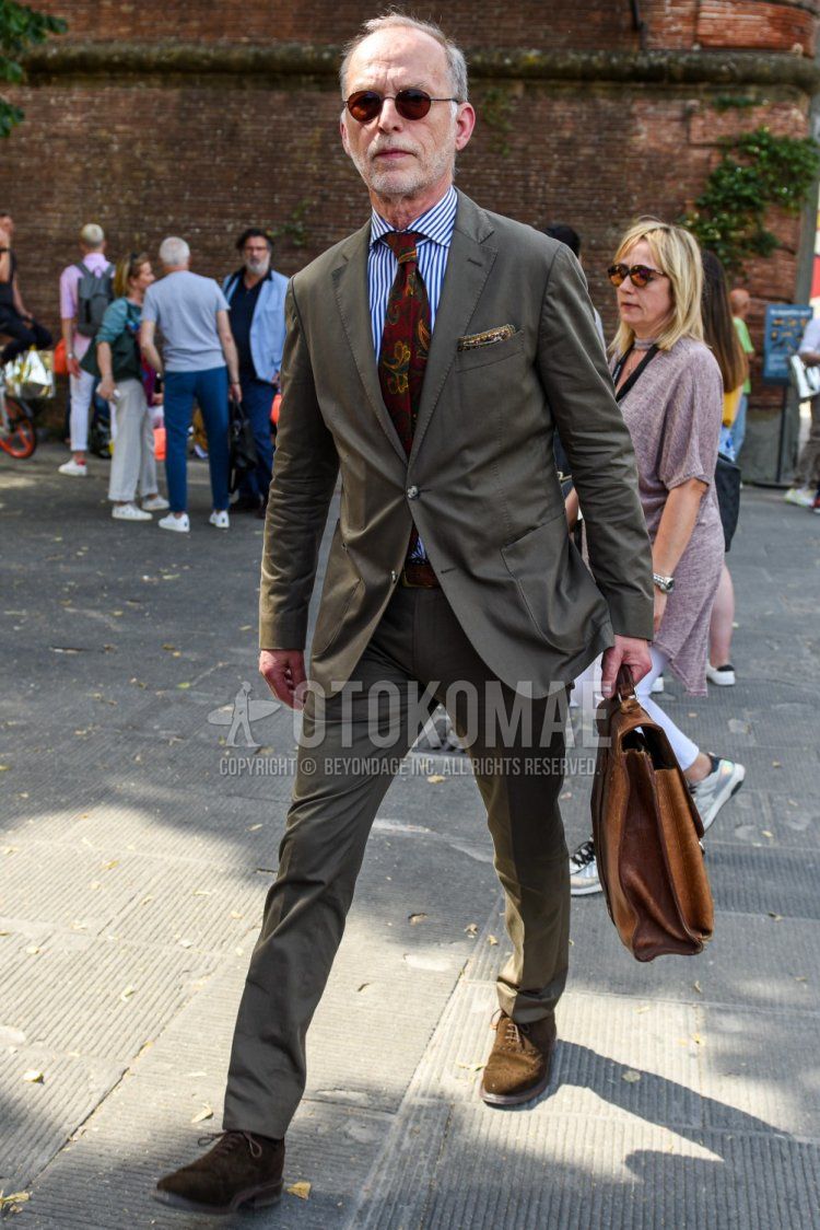 Men's spring/summer/fall outfit with plain brown sunglasses, blue/white striped shirt, brown suede shoes leather shoes, plain brown briefcase/handbag, plain olive green suit, red tie tie.