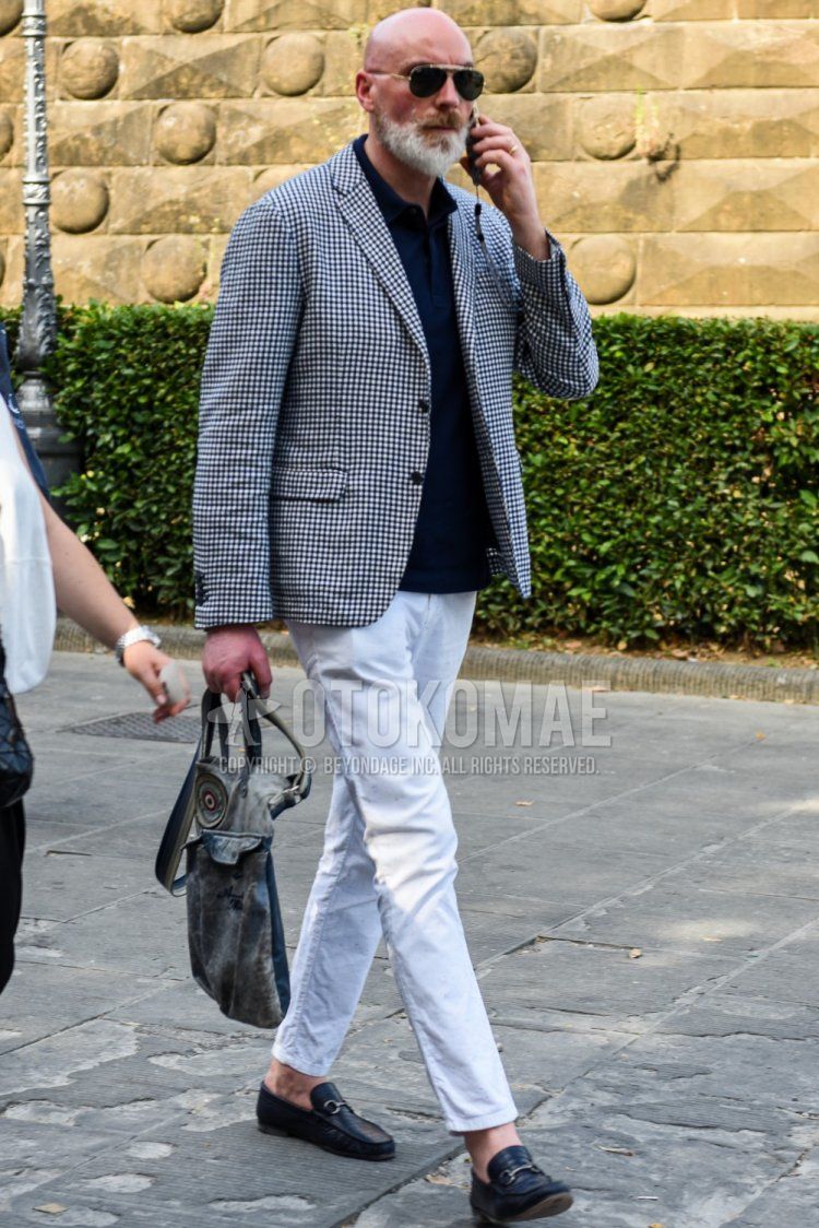 Teardrop black and gold solid sunglasses, black and white checked tailored jacket, solid navy polo shirt, solid white ankle pants, solid cotton pants, black bit loafer leather shoes, and solid gray briefcase/handbag for men in spring, summer and fall. Outfit.